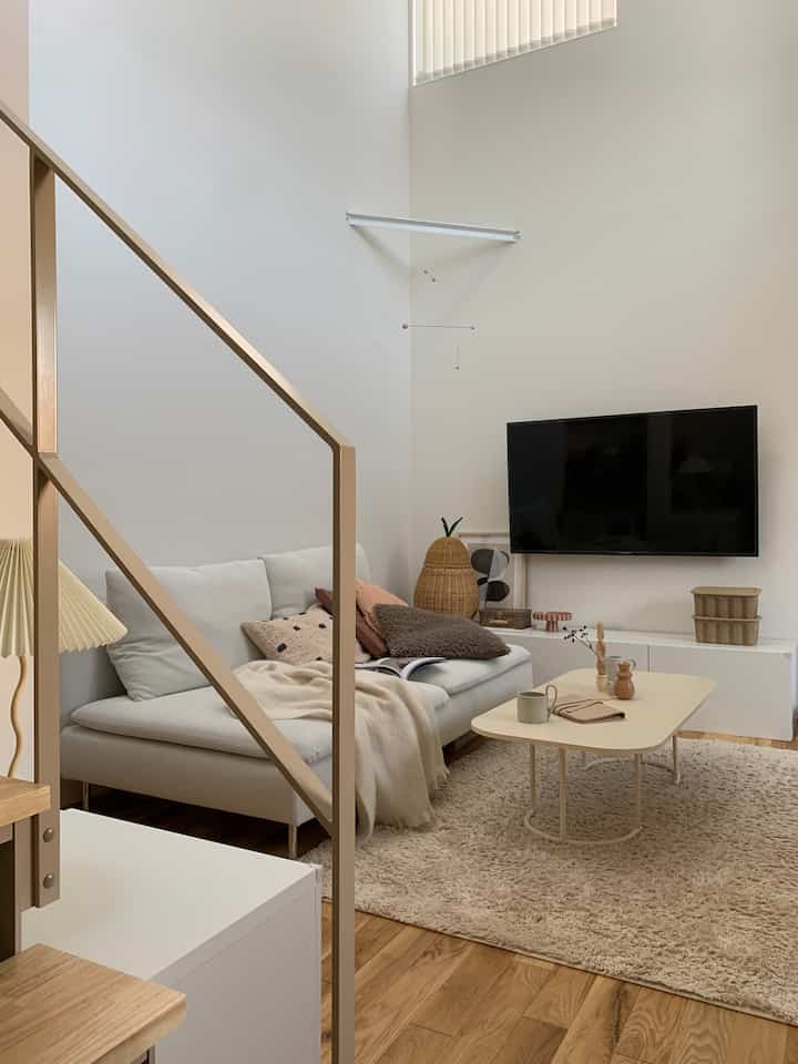 White and beige toned living room featuring a white sofa, shaggy rug, and coffee table in a modern natural style
