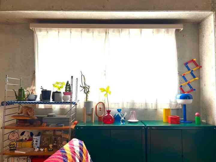 透明なガラスの花瓶や多彩な小物が配置された明るくすっきりとしたモダンな狭い部屋、緑色の収納棚が印象的なインテリア