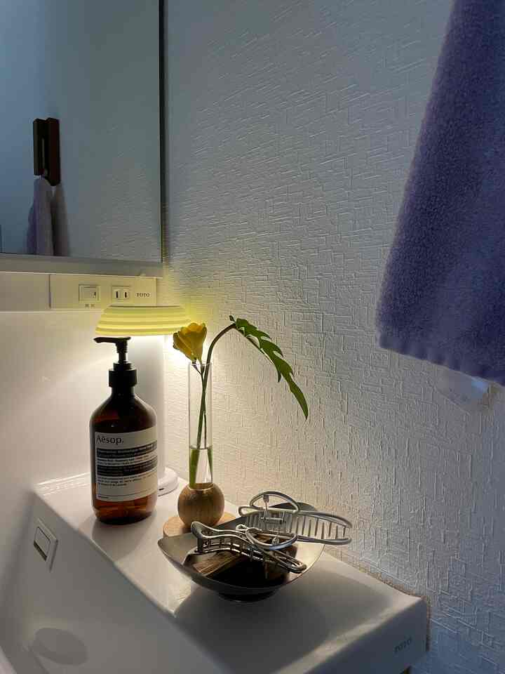 White-toned bathroom space featuring a purple towel and aromatic handwash with a cozy and clean atmosphere