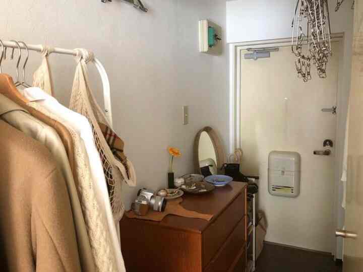 ナチュラルなベージュトーンの狭い玄関、ハンガーラックと収納チェストが配置された雰囲気のあるインテリア