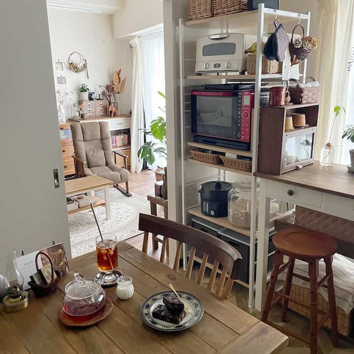 ブラウンとナチュラルな色調のダイニングルーム、木製のテーブルと椅子、食器類、そして落ち着いたおうちカフェの雰囲気があるインテリア