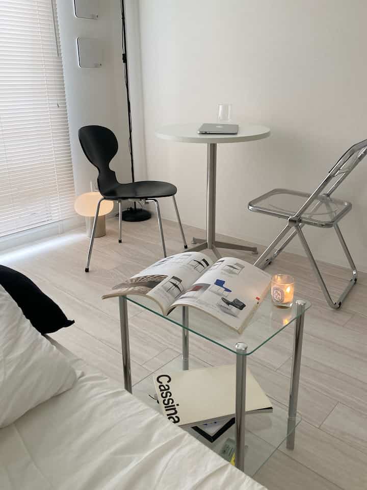 モノトーンと透明素材が調和したリビング、黒い椅子とガラスのサイドテーブルが配置されたシンプルで落ち着きのある空間