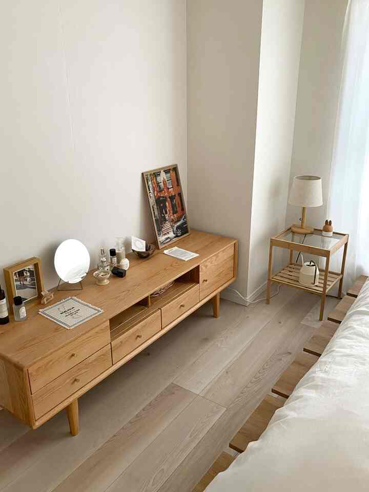 Natural tone bedroom featuring wooden TV stand and side table, white bedding creating a clean atmosphere