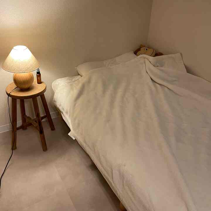 Cozy bedroom in beige and wood tones featuring a bed and nightstand with a warm table lamp