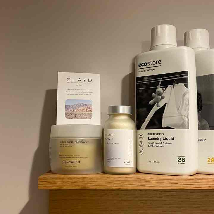 Natural wood tone wall-mounted shelf in bathroom featuring neatly arranged bath and laundry products with a minimalist natural vibe