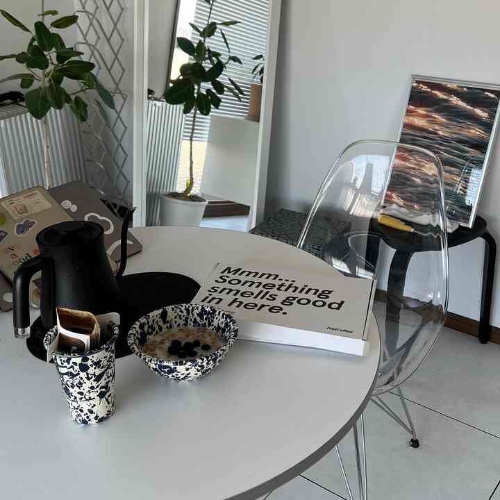 White-toned kitchen space featuring a modern transparent chair and round table with a simple interior design