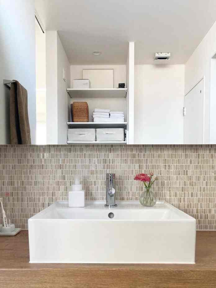 White and brown toned bathroom sink area with organized shelves and accessories, featuring a simple and clean atmosphere