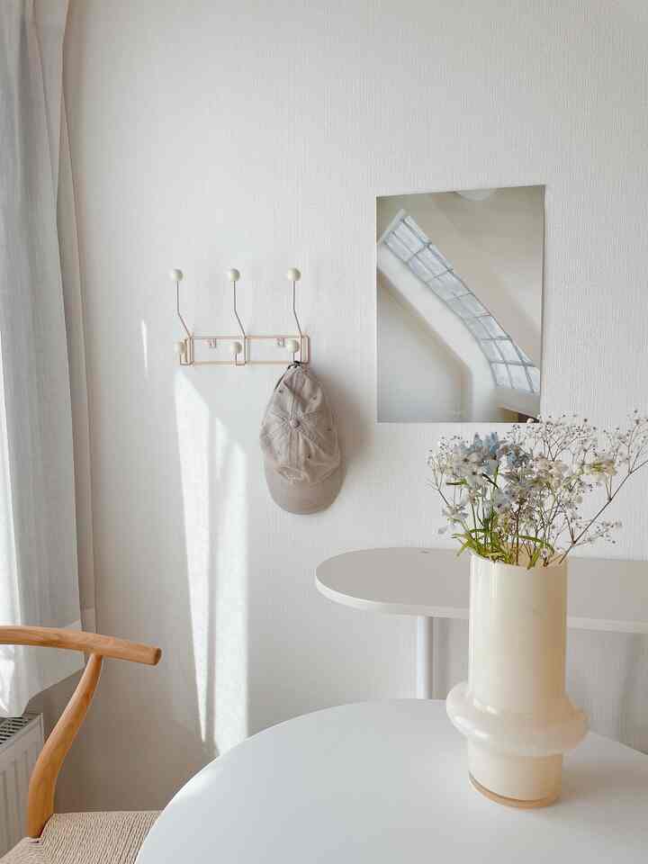 Bright white-toned living space with a milky vase of flowers on round table, featuring simple and fresh interior design