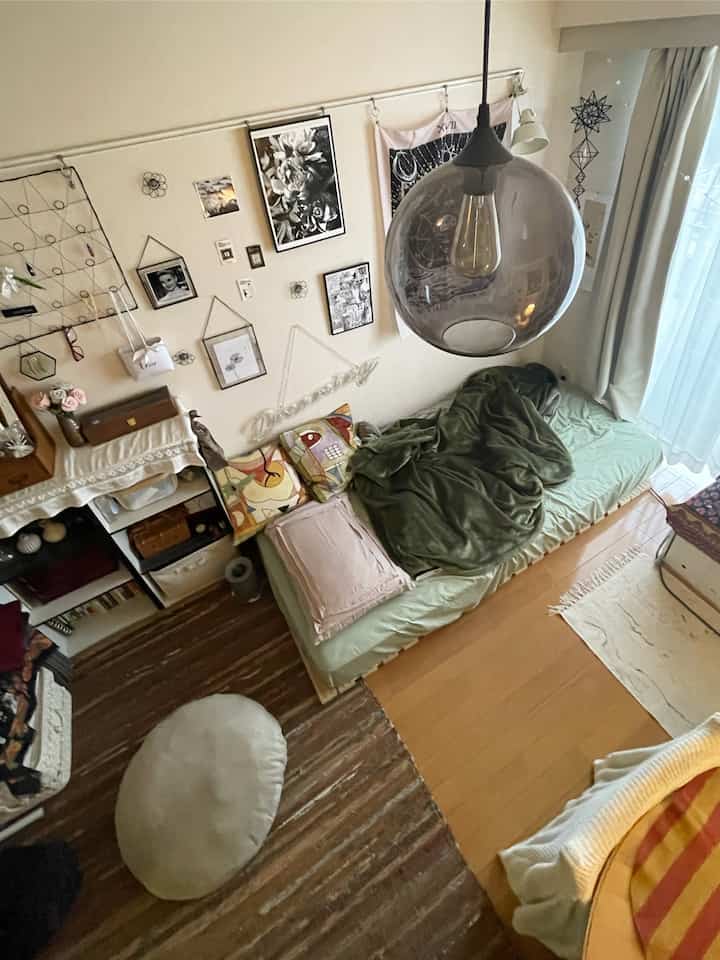 ナチュラルカラーの一人用ベッドとペンダントライトが配置された、落ち着いた雰囲気の小さな部屋のインテリア