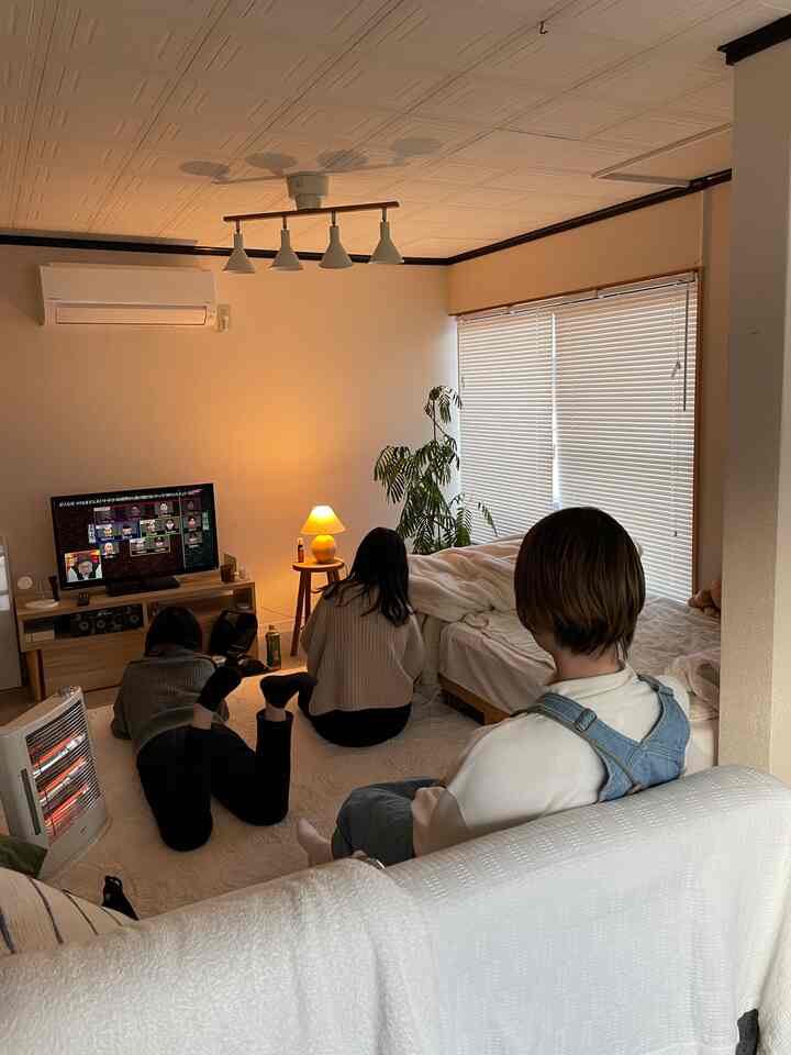 白とナチュラルな色調のリビング、ラグの上に3人が座ってテレビを見ている雰囲気のある空間