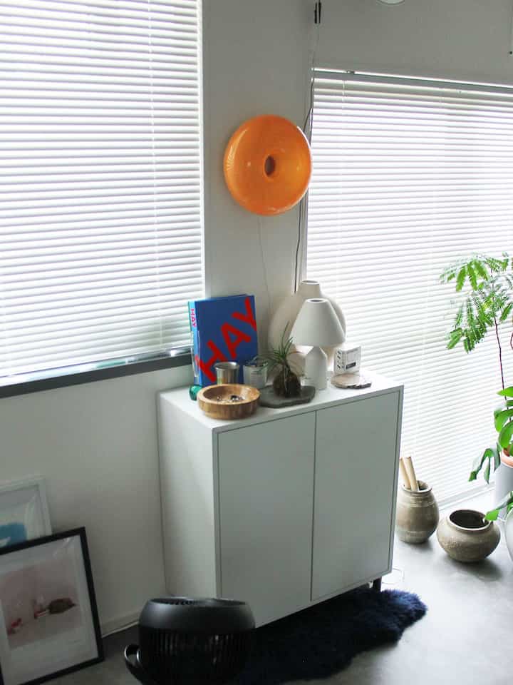 White and natural-toned entrance or dining room featuring plants and bookshelf with a clean, modern atmosphere