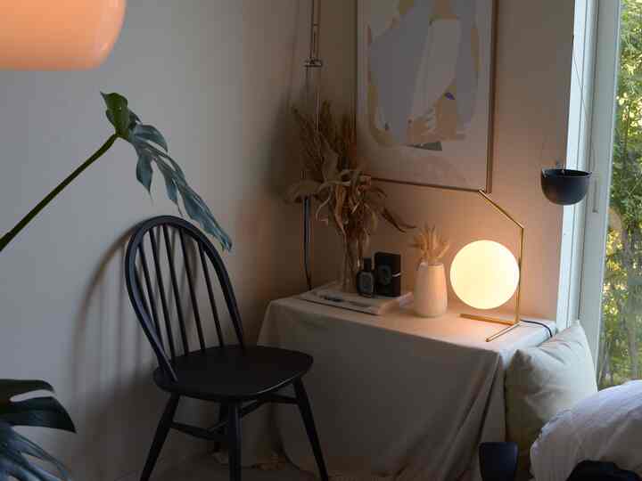Ivory-toned bedroom featuring a black chair and glowing table lamp beside a cozy bed