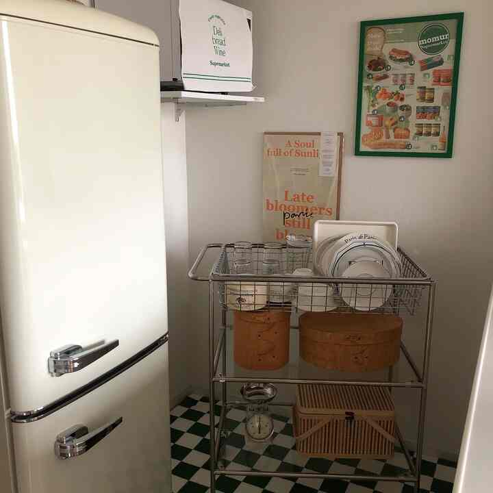 白と緑の色調のキッチン、ヴィンテージの冷蔵庫とキッチンワゴンが配置されたミニマルな雰囲気のあるインテリア