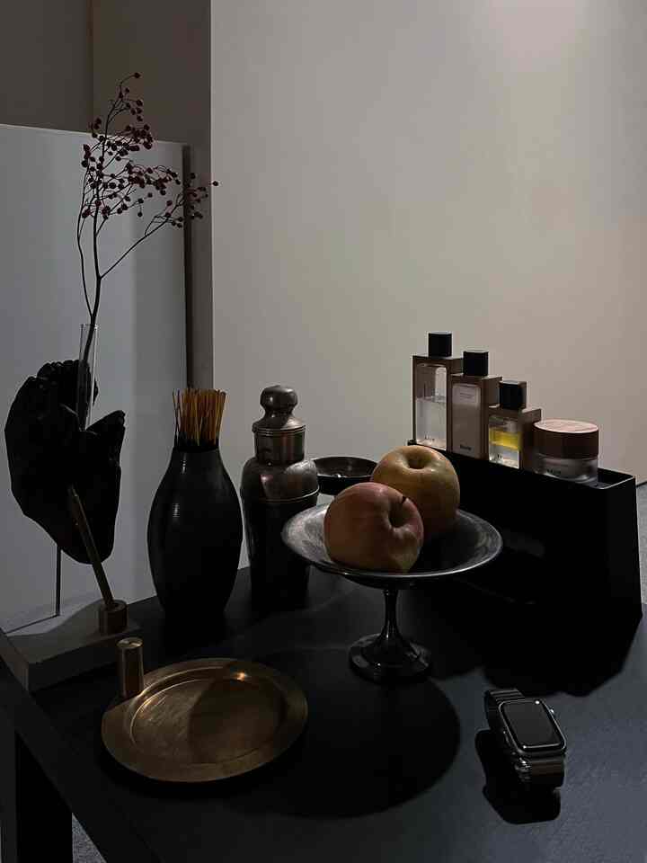 黒いテーブルの上に金色のトレイや香水、リンゴが配されたミニマルでナチュラルなインテリア