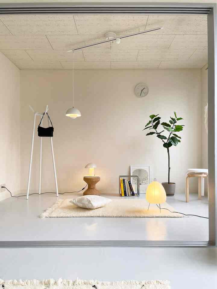 柔らかなアイボリーのナチュラルカラーのリビング、ペンダントライトとフロアランプが配置されたシンプルで落ち着いた空間