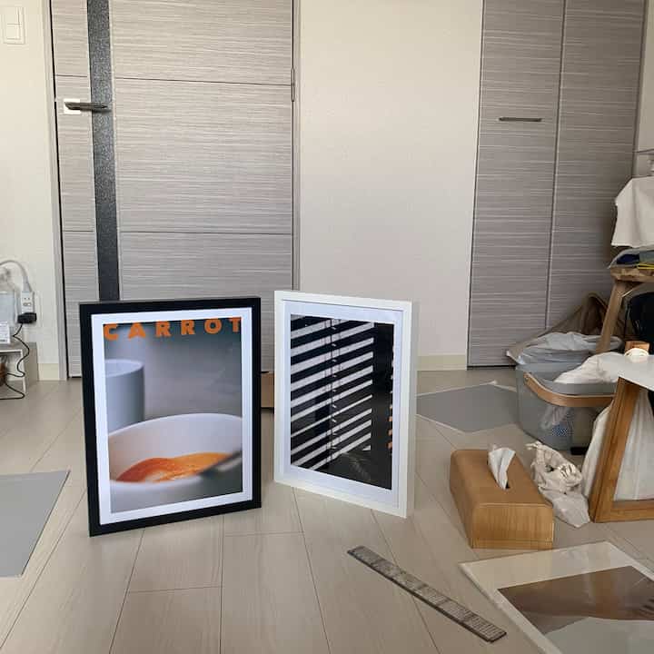 明るいホワイトとグレーのトーンでまとめられた小さな空間、床に置かれた2つのポスターがあるシンプルなインテリア