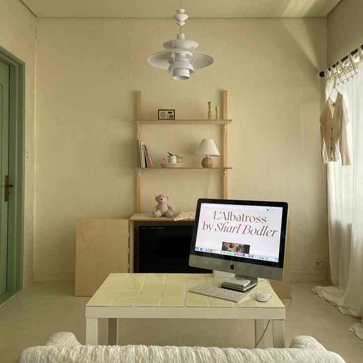Beige and natural-toned compact home office with a green door and white curtains, featuring simple modern interior