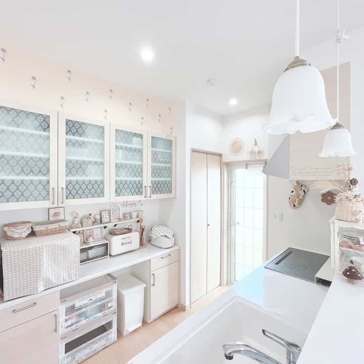 白とナチュラルウッド調のキッチン、ペンダントライトが配置された清潔で居心地の良い空間