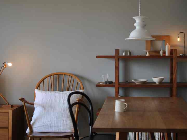 木目調と白の落ち着いたリビング、ヴィンテージのアームチェアとペンダントライトが配置された雰囲気のあるインテリア