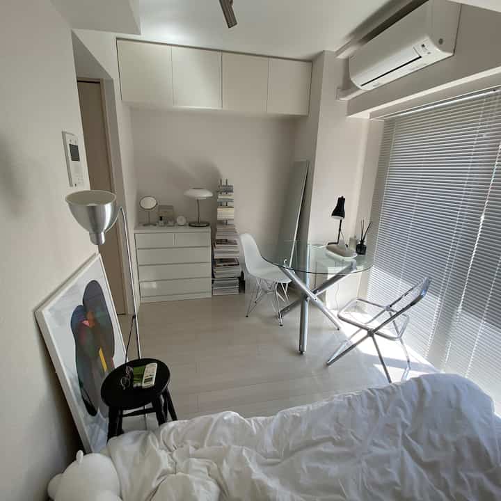 白を基調としたコンパクトな一人暮らしの部屋、ガラステーブルとシンプルな家具が配されたナチュラルモダンなインテリア