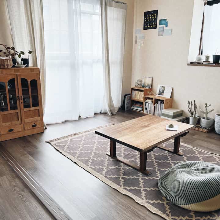 ナチュラルカラーのリビング、中央に座卓とプーフクッションが配置された雰囲気のある空間