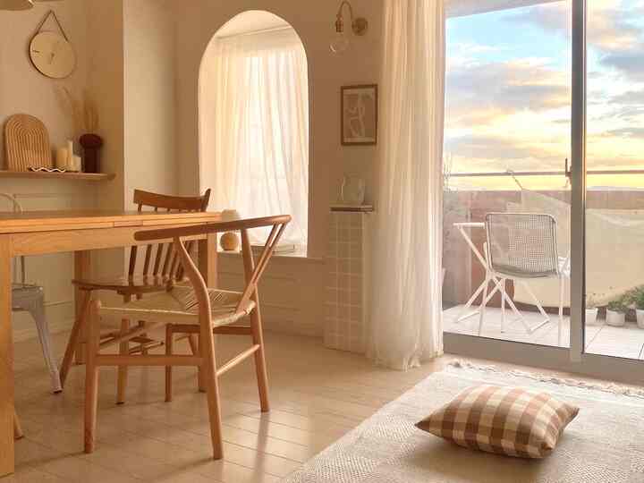 Beige and wood tone dining and living room featuring an arch wall and large glass doors creating a cozy atmosphere