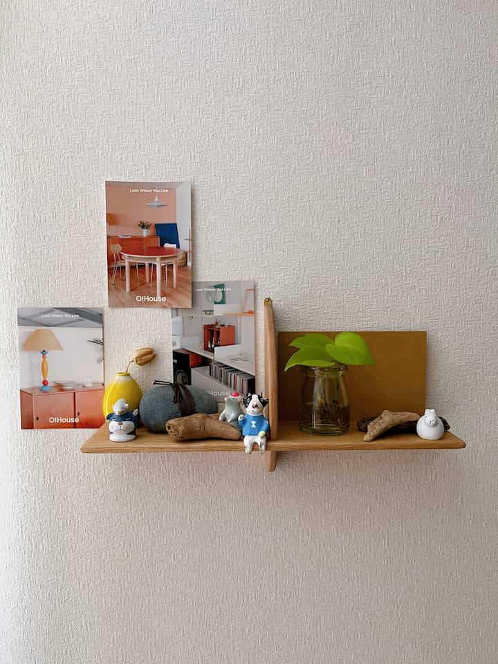 Simple and cozy space with a wood wall-mounted shelf and assorted small decorative items on a beige wall