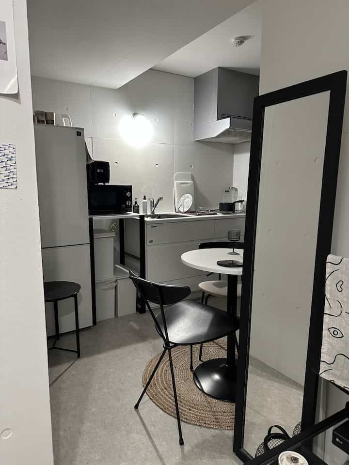 白と黒の色調でまとめられた小さなキッチンとダイニングテーブルが配置された清潔で居心地の良い一人暮らしの空間