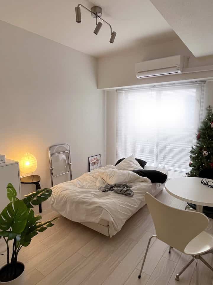 白と緑のトーンの寝室、中央に配置されたベッドと小さなダイニングテーブルがあるミニマルな印象的な空間