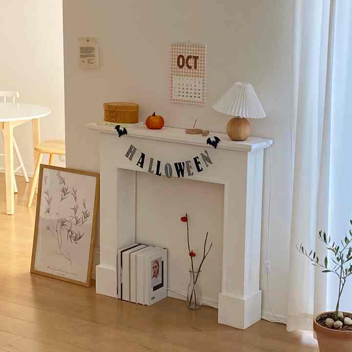 白と木目調のダイニングルーム、フロアポスターとテーブルランプが配置されたミニマルで落ち着いた雰囲気のインテリア