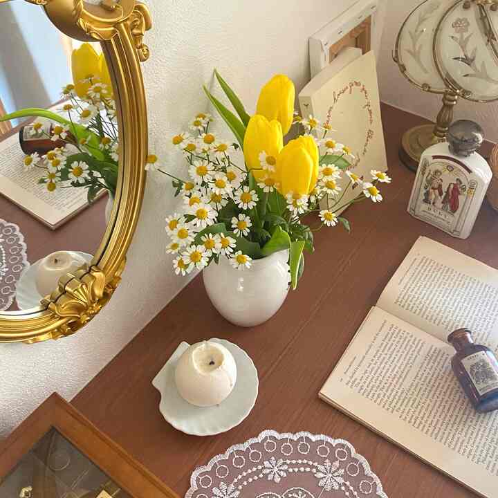 温かみのある木目調と北欧風のドレッサー、黄色いチューリップとデイジーの花瓶、ゴールドフレームの鏡が配置された雰囲気のある空間