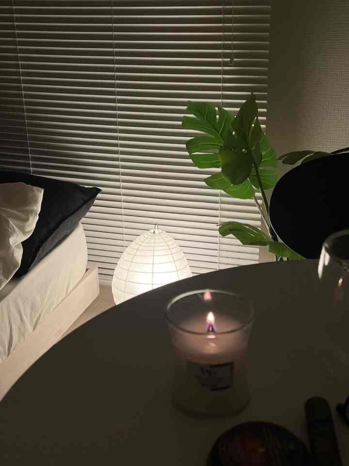 Calm white and natural wood toned bedroom featuring aroma candle and Isamu Noguchi Akari lamp creating warm atmosphere