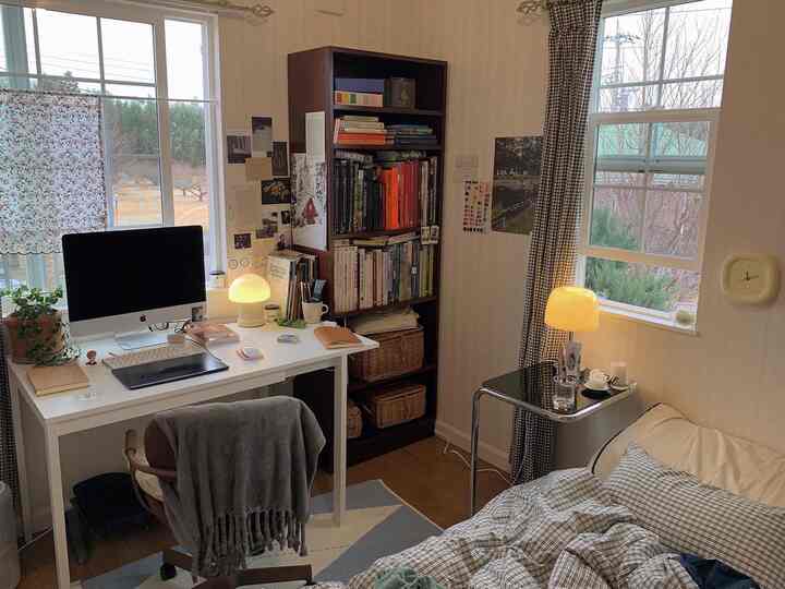 Natural-colored and calm-toned study-bedroom space featuring a white desk and brown bookshelf, creating a cozy atmosphere