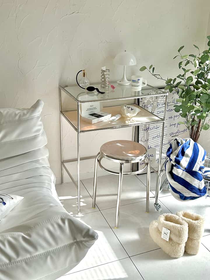 白とシルバーの色調のリビング、ソファとステンレス製の化粧台が配置された清潔感のあるモダンなインテリア