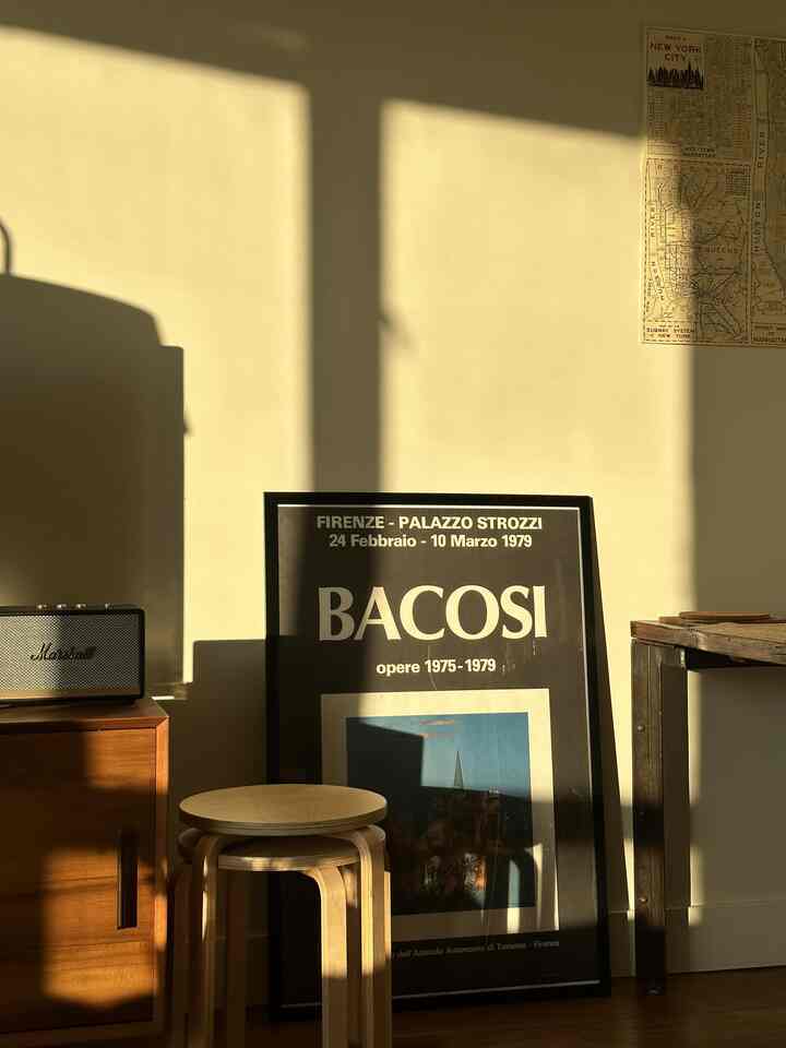 Warm wood tones and beige walls define a mid-century modern living room featuring stools and a media console bathed in natural light