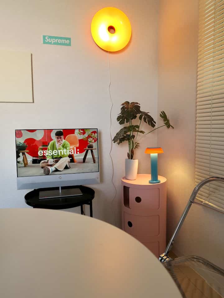 モノトーンの背景にピンクの収納と暖かな照明が調和したコンパクトなリビング空間