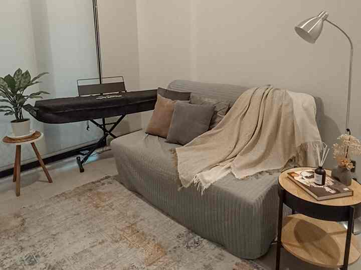 Natural color toned living room featuring a gray sofa with beige throw blanket and wooden side tables, creating a cozy atmosphere
