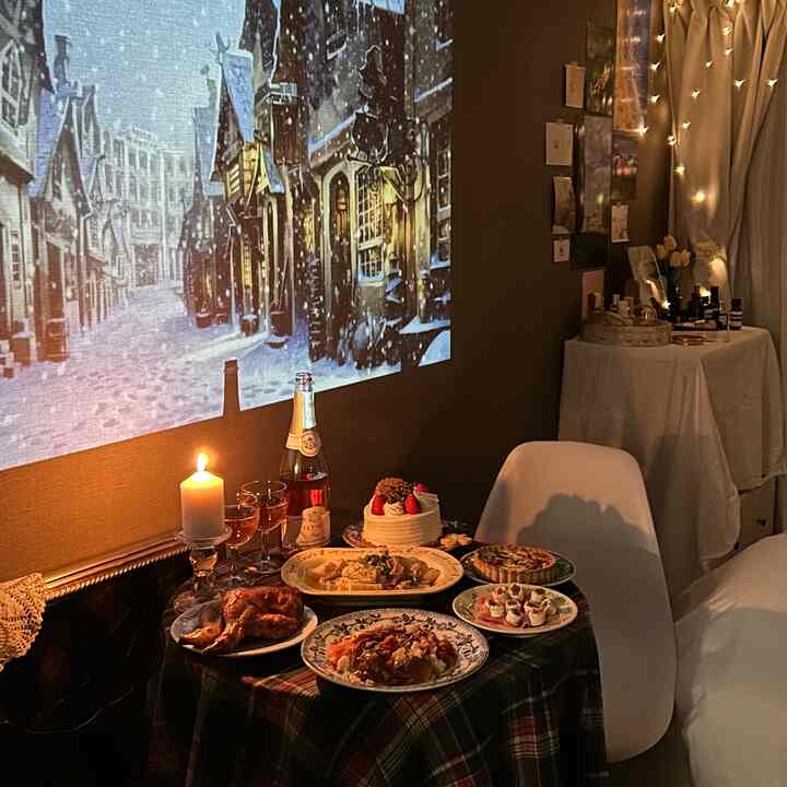 赤いチェックのテーブルクロスがかかったダイニングテーブルと白い椅子、壁に冬の街並みが映された雰囲気のある小さなホームパーティースペース