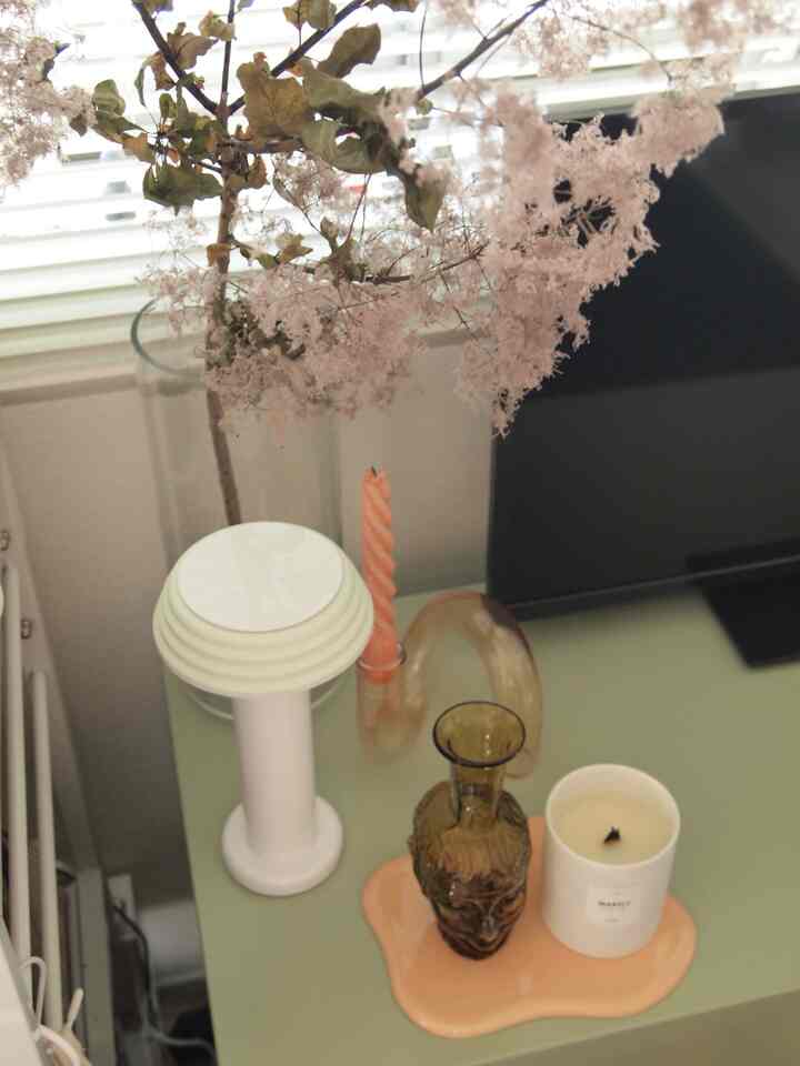 Natural modern interior with white and brown tones featuring a portable lamp, vase, and candle on a table.