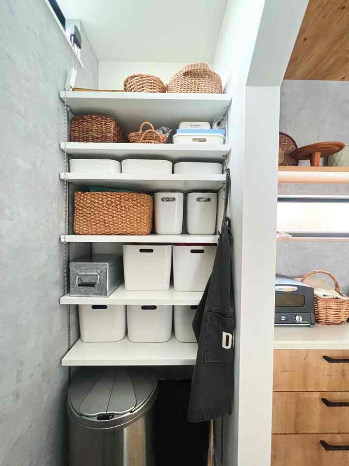 白と茶色の調和が取れたパントリー空間、統一された収納ケースとバスケットが整理されたキッチン脇の収納スペース