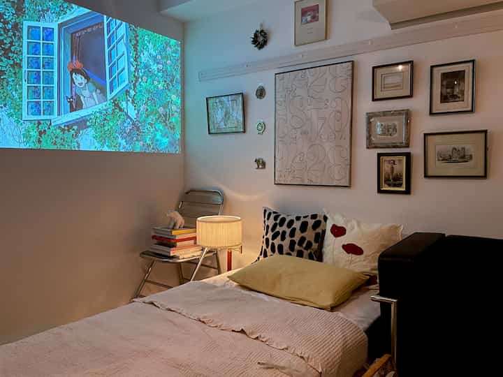 白い壁とミニマルな寝室、黄色いクッションとテーブルランプが暖かい雰囲気を醸し出す空間