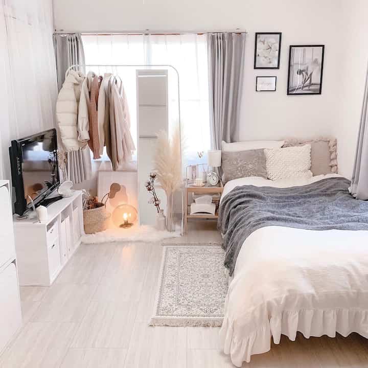 明るいホワイトとライトグレーの寝室、全身鏡とベッド、掛け布団カバーが特徴のシンプルでナチュラルなインテリア