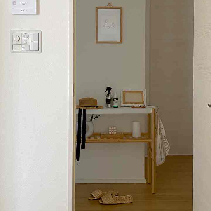 ナチュラルな色調の玄関、木製の棚と整った小物が配置されたシンプルなインテリア