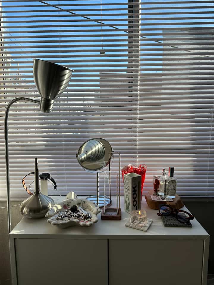 白とシルバーのトーンのサイドボードに多様な小物とフロアランプが配置された雰囲気のある空間