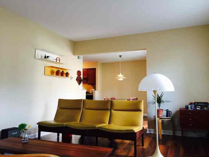 Natural-toned living room with yellow sofa and wooden floor, featuring a white floor lamp and pendant lighting in background