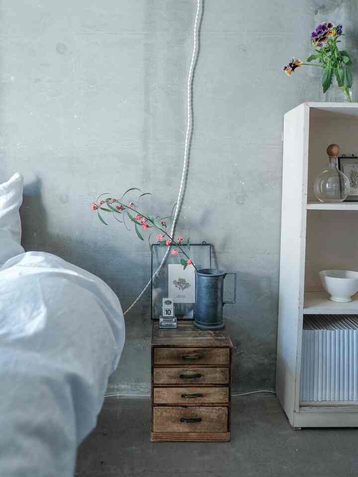 Simple bedroom with gray concrete wall and natural wood chest of drawers
