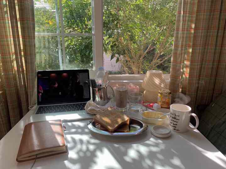 白いテーブルが置かれた居心地の良いダイニングルーム、チェックのカーテンと窓から自然光が差し込むホームカフェの雰囲気のある空間