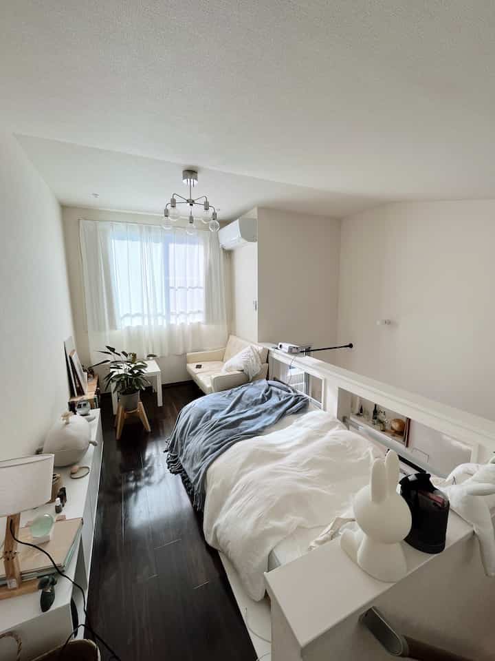 白と茶色のトーンの6畳ワンルーム寝室、ベッドとソファが配置されたナチュラルモダンスタイルの空間