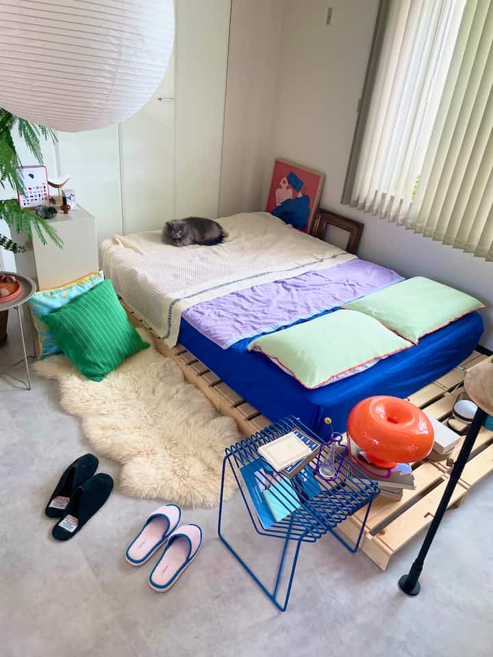White and blue toned bedroom featuring a wooden bed with lavender blanket and a cat resting