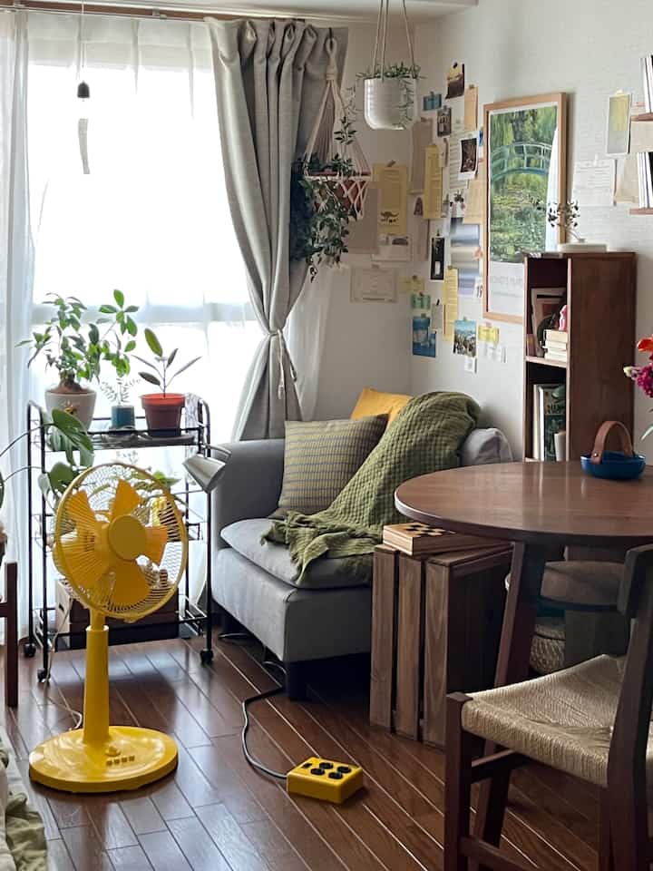 ナチュラルな雰囲気の一人暮らしリビング、グレーのソファと木製の円形テーブルが配置された印象的な空間